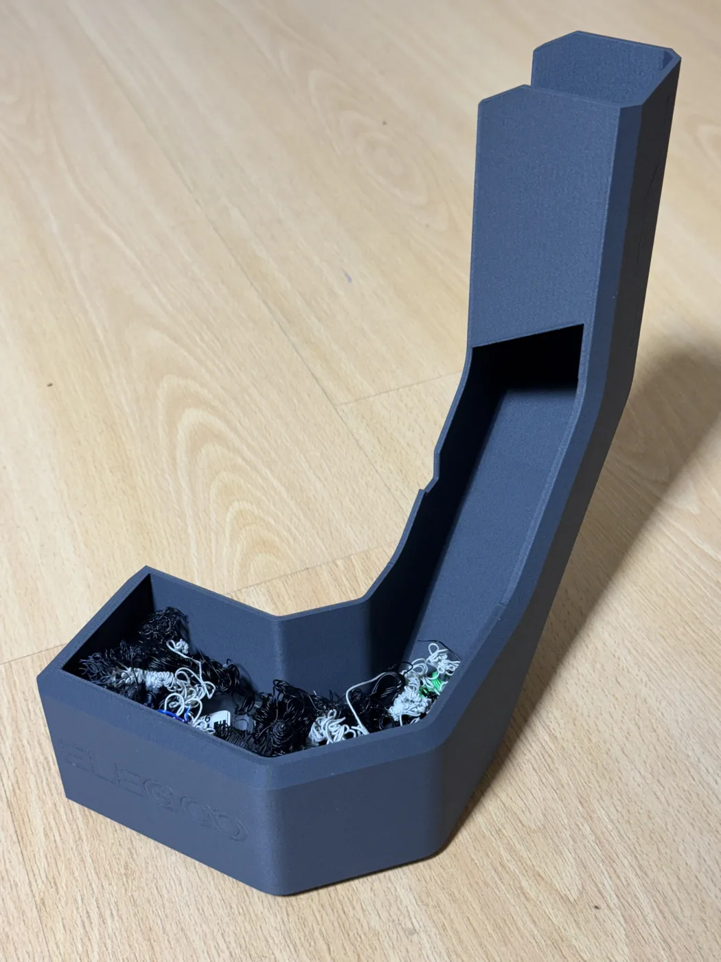 Goulotte à purges vue de profil, remplie de déchets de filament